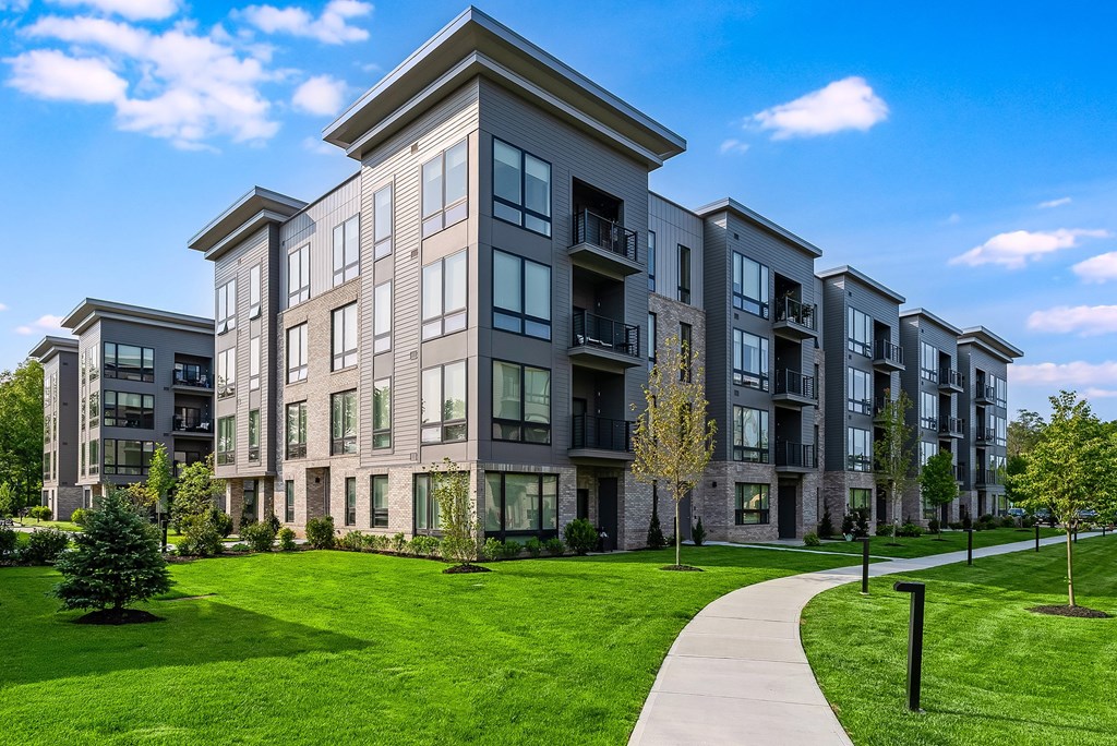 A modern apartment building with a well-maintained lawn in front.