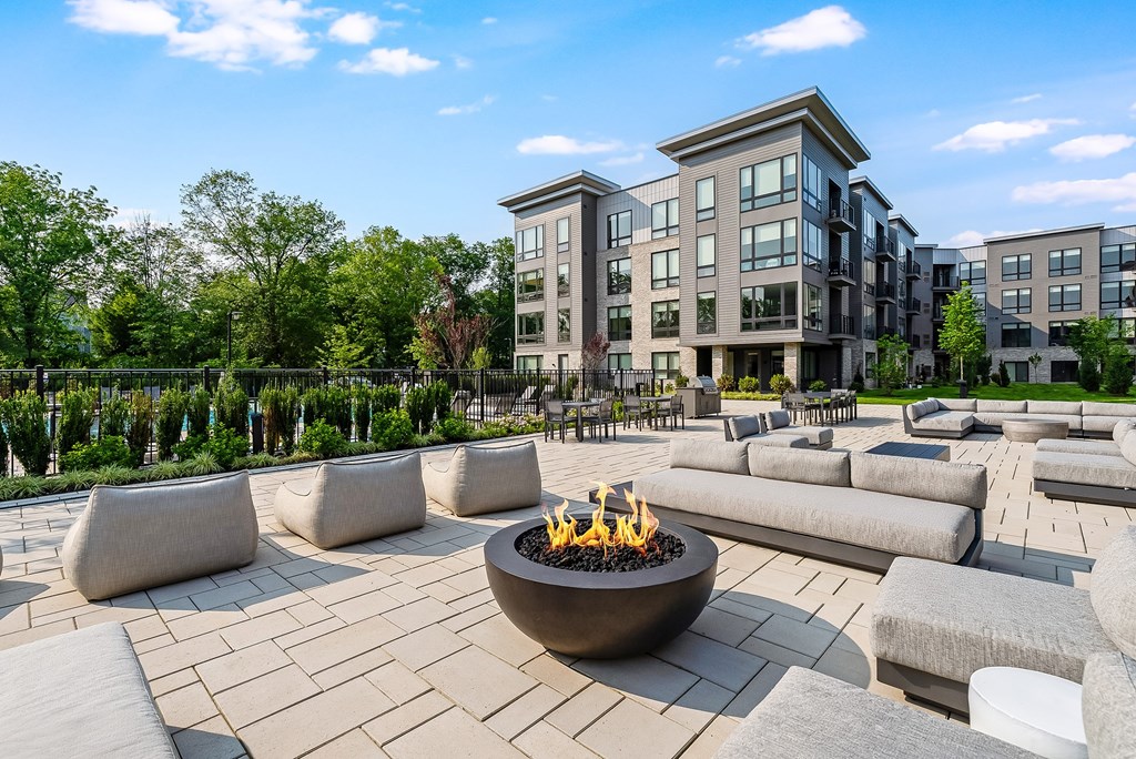 A modern outdoor seating area with a fire pit in the center.