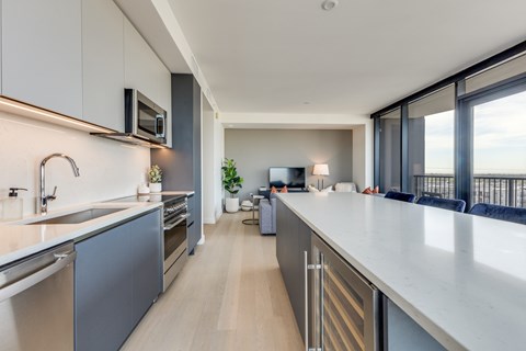 A modern kitchen with a long counter and stainless steel appliances.
