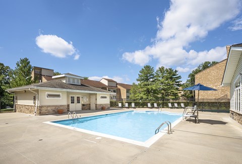 A swimming pool in a backyard with a house and trees in the background.
