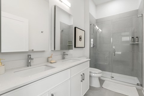 A white bathroom with a toilet, sink, and shower.