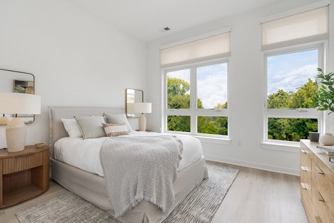 A bedroom with a large bed and a view of trees outside the window.
