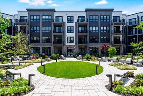 A modern apartment complex with a circular garden in the foreground.