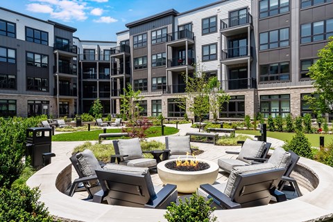 A modern outdoor seating area with a fire pit in the center.