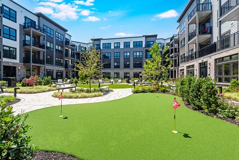 A miniature golf course is located in the courtyard of apartment buildings.