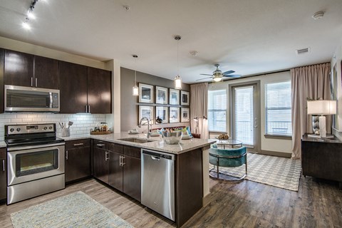 A modern kitchen with dark wood cabinets and stainless steel appliances.