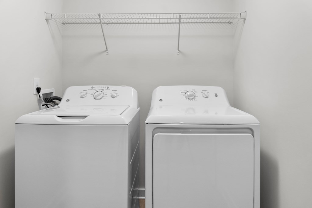 Two white front loading washing machines in a laundry room at Grand at Pearl Apartments, Mississippi