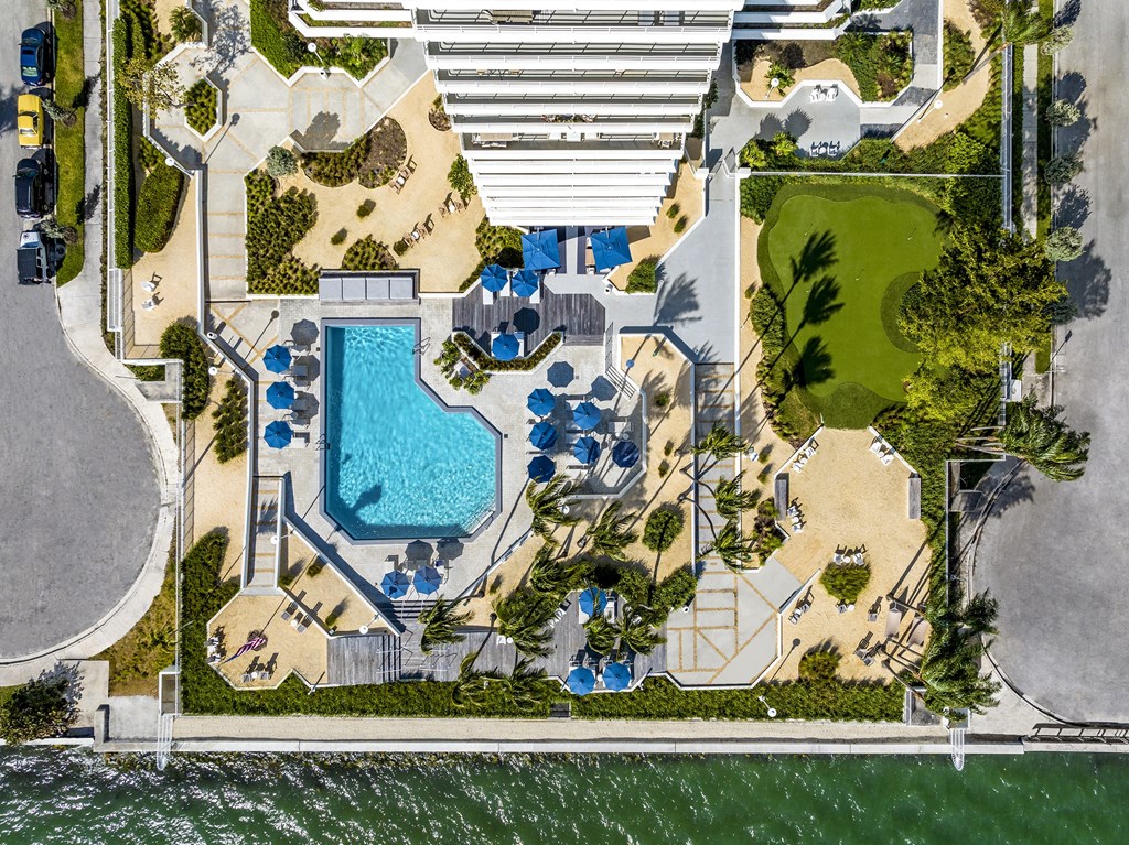 An aerial view of a beachfront with a swimming pool and a parking lot.