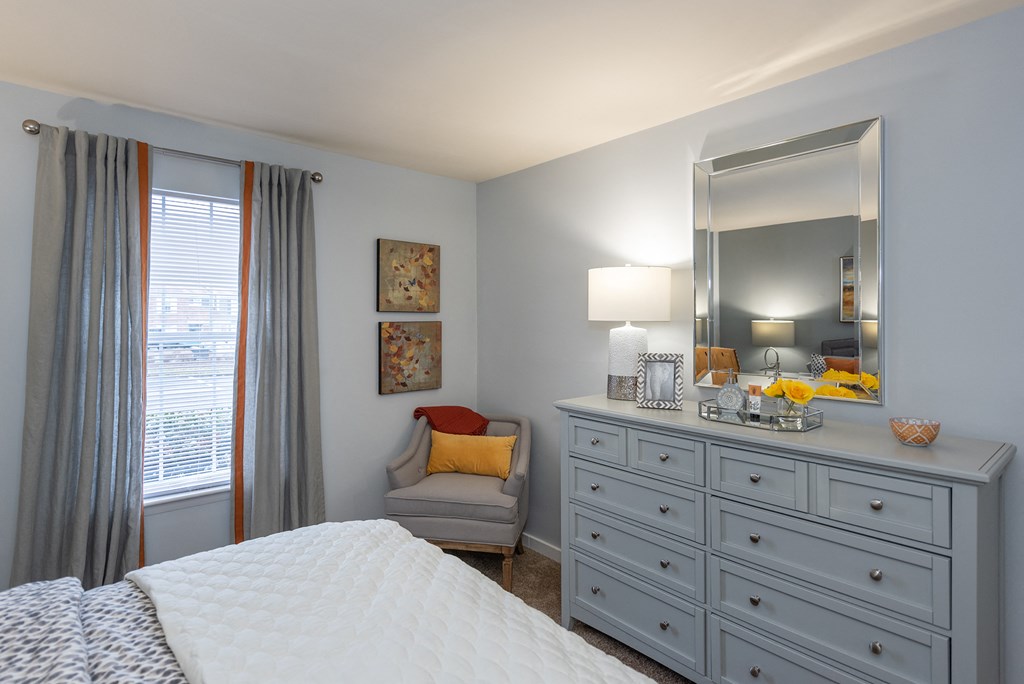 a bedroom with a bed and a dresser with a mirror