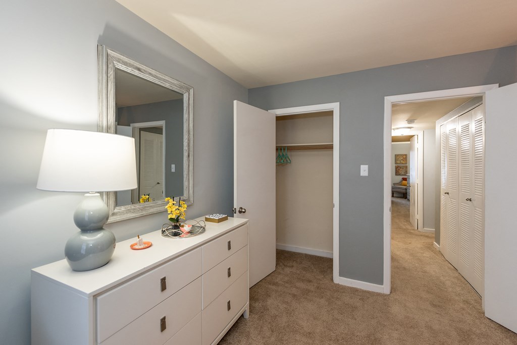 a bedroom with a white dresser and a mirror and a hallway with a closet
