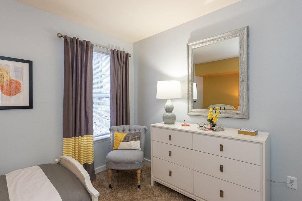 a bedroom with a bed and a dresser with a mirror