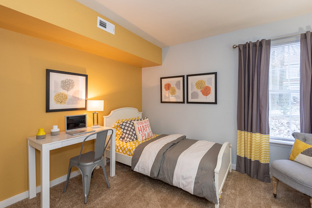 a bedroom with a bed and a desk with a computer