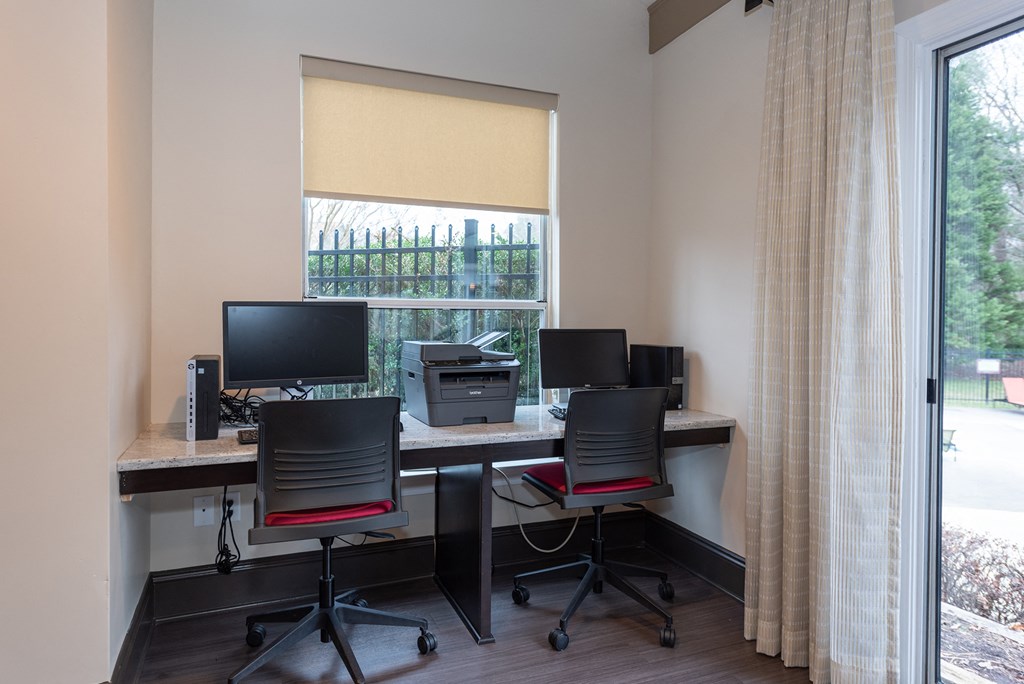 an office with two desks with computers and a window