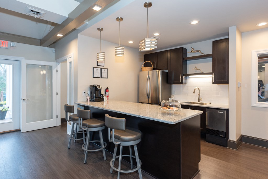 a kitchen with a large island with bar stools and a stainless steel refrigerator