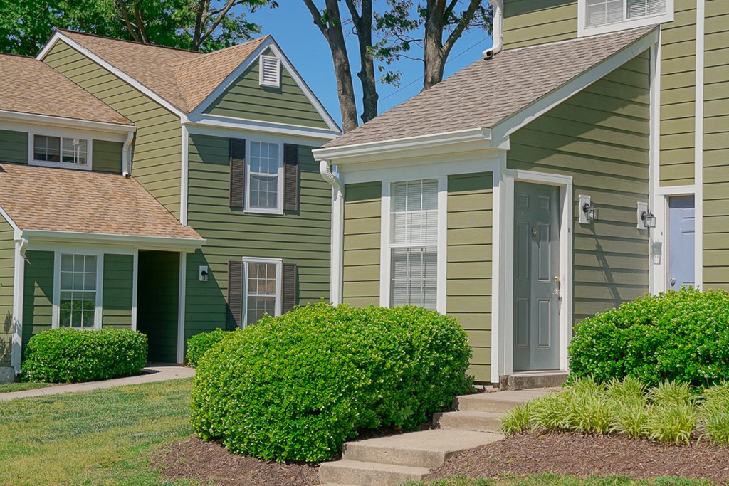 a row of houses with green siding and a grassy yard