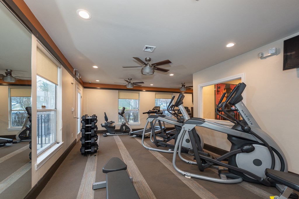 a home gym with exercise equipment and a ceiling fan