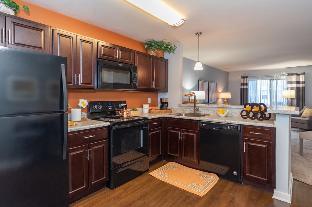 full kitchen with black appliances and brown cabinets at the reserve at walnut creek apartments