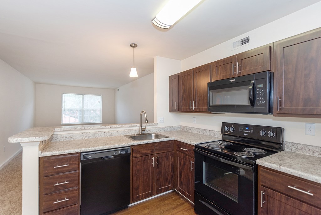 a kitchen with black appliances and granite counter tops and wooden cabinets