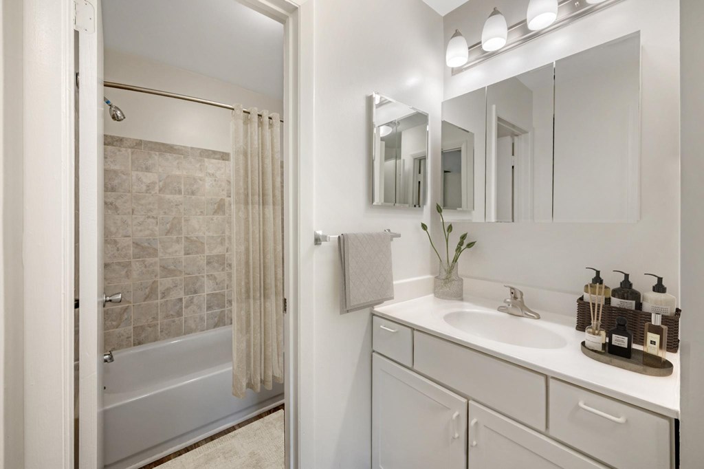 A bathroom with a white tub, sink, and mirror.