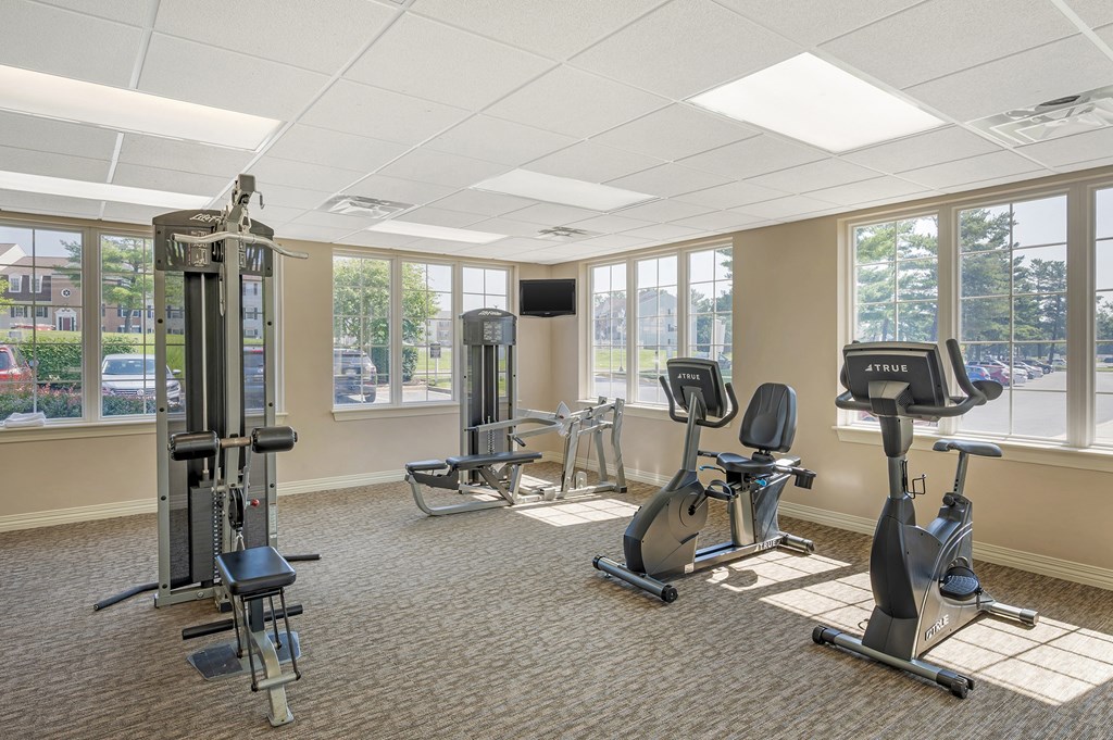 A gym with a variety of equipment including a treadmill, elliptical machines, and a weight machine.