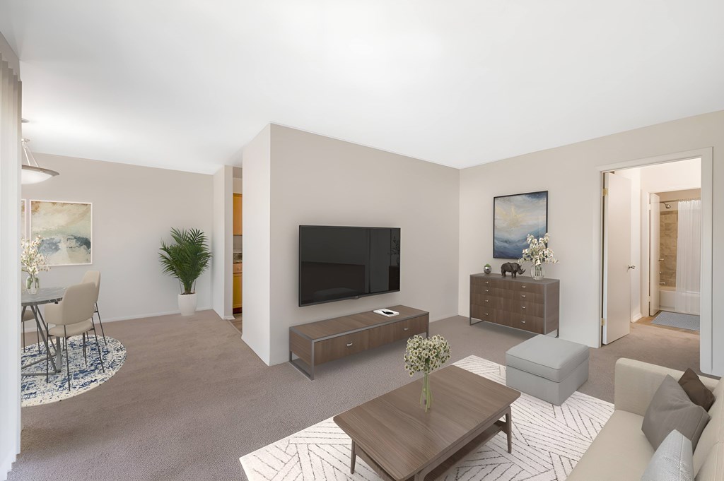 A living room with a television, a couch, a coffee table, and a plant.