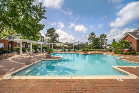 A large outdoor swimming pool surrounded by a brick patio.