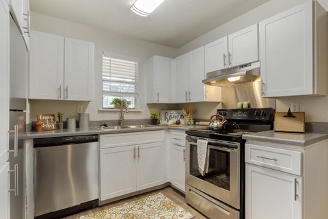 A kitchen with white cabinets and a patterned floor mat.