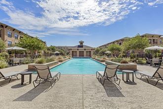 a swimming pool with chairs and umbrellas and a building in the background
