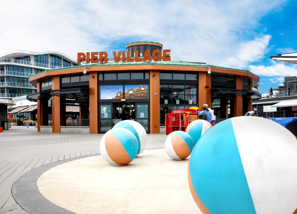A large building with a sign that says "Pier Village" in front of it.