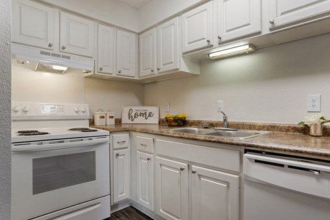 A kitchen with white cabinets and a white stove.