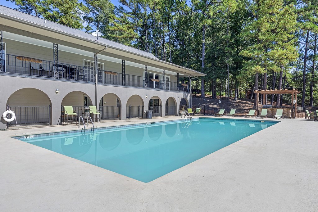 the swimming pool at our apartments with a building and trees