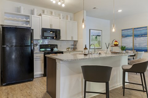 a kitchen with a large island and a black refrigerator