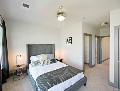 A bedroom with a large bed and a nightstand with a lamp.