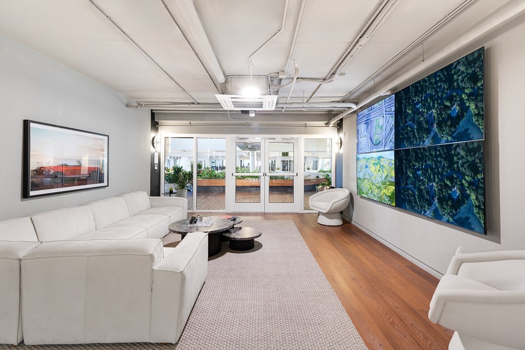 A white couch is in the middle of a room with a large window.