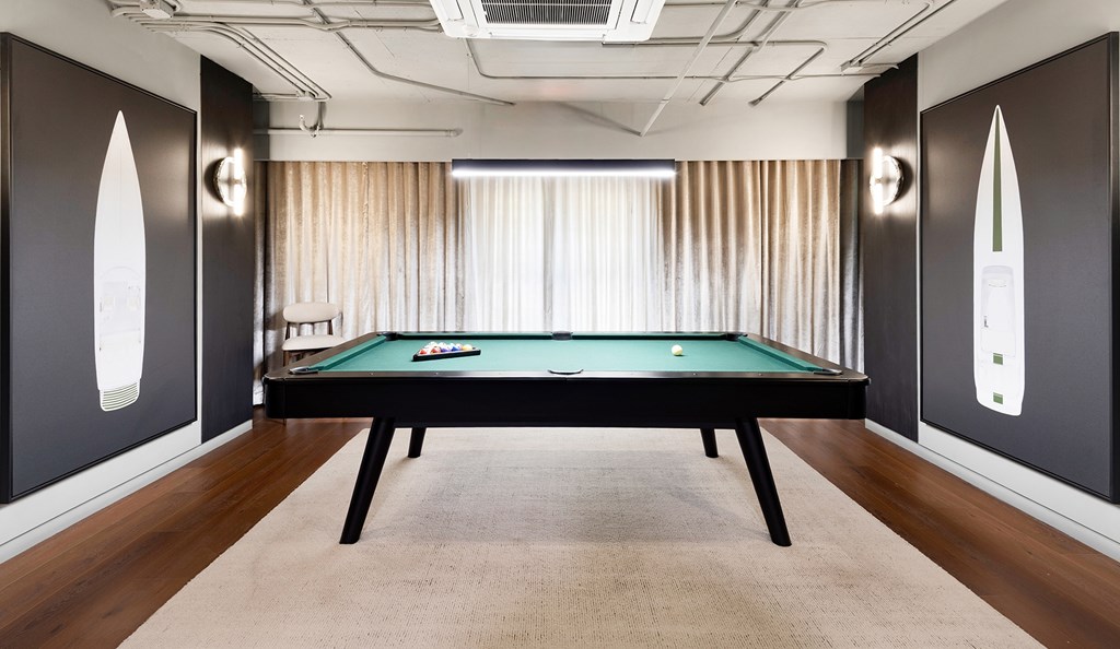 A pool table in a room with dark walls and a light-colored carpet.