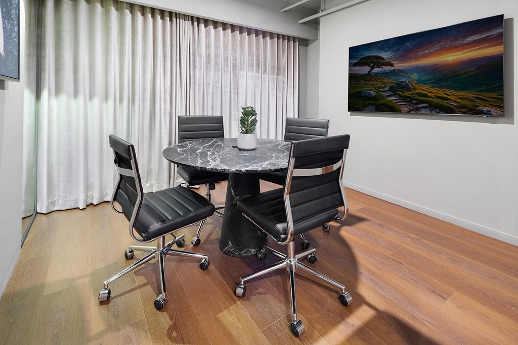 A conference room with a table, chairs, and a painting on the wall.