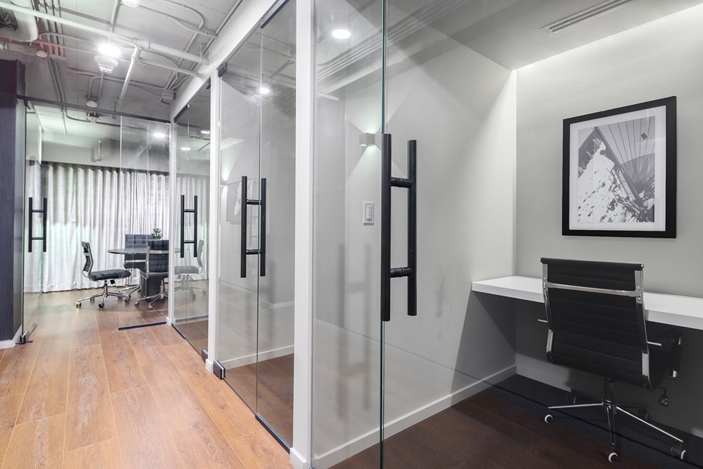 A modern office with glass walls and a wooden floor.