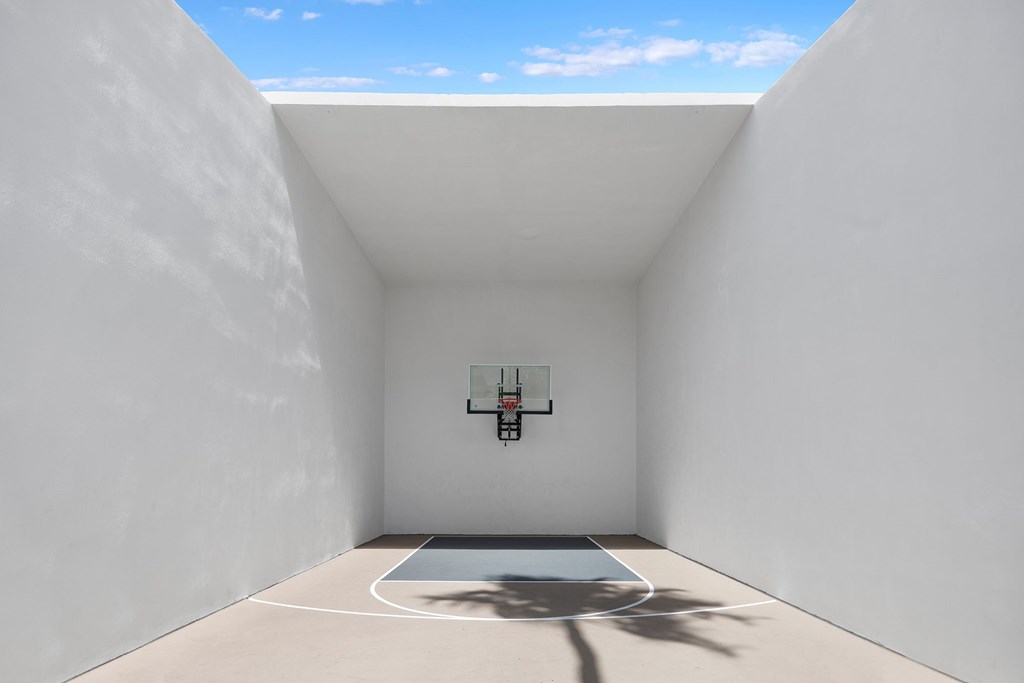 A basketball hoop is mounted on a wall in a white room.