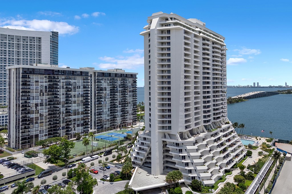 A tall white building with a pool in front of it.