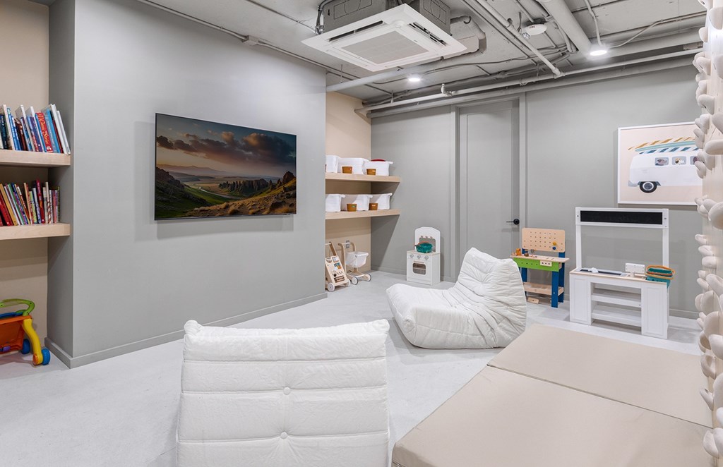 A room with a white chair, a white sofa, and a painting on the wall.