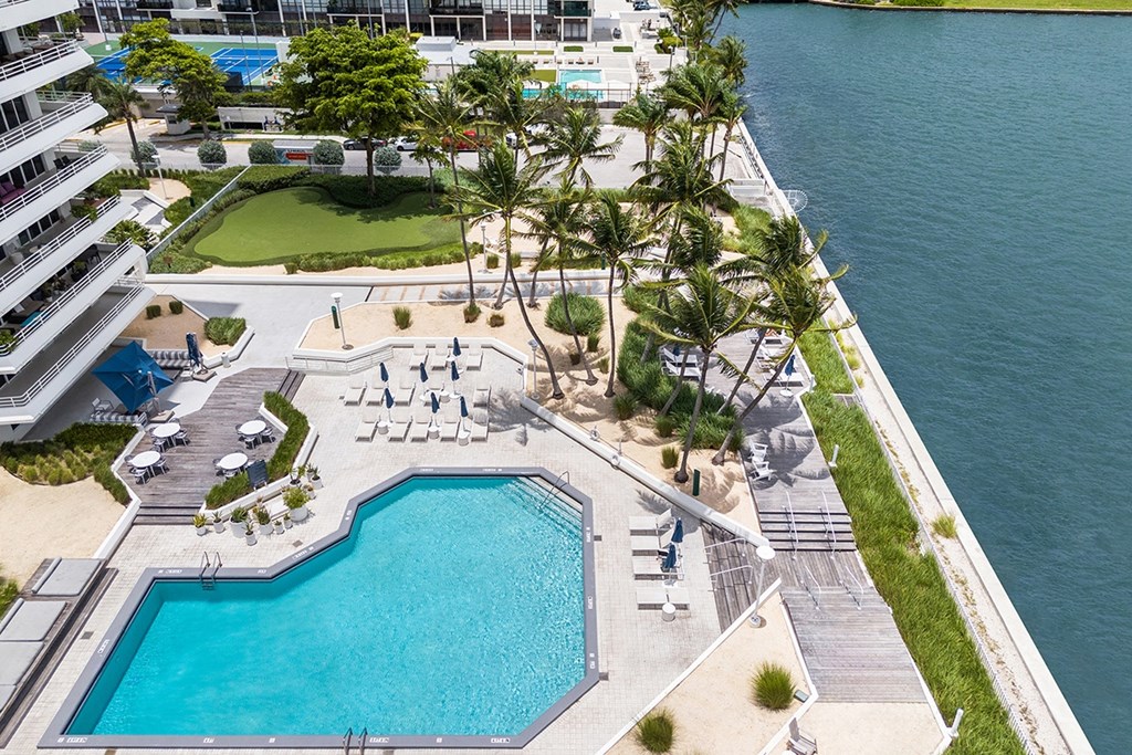 A large swimming pool with a small one next to it and a grassy area with trees.