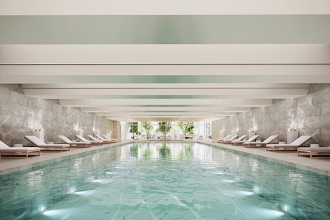 A large indoor swimming pool with lounge chairs on either side.