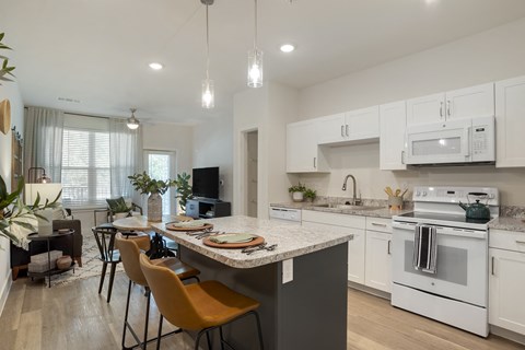 an open kitchen and dining area with white appliances and a marble counter top