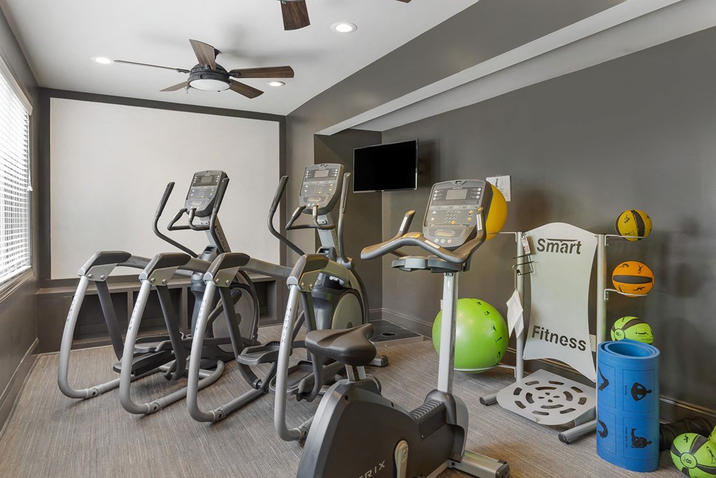 a gym with various exercise machines and a television