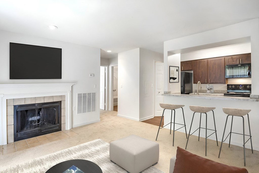 a living room with a fireplace and a bar with stools