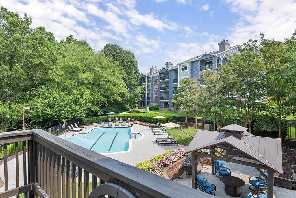 a view of a swimming pool with a patio with chairs and umbrellas
