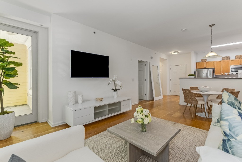 A living room with a white couch, a grey coffee table, and a flat screen TV mounted on the wall.
