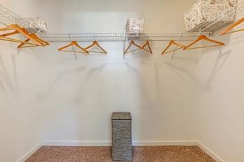 A room with a white wall and a wire shelf with orange hangers.