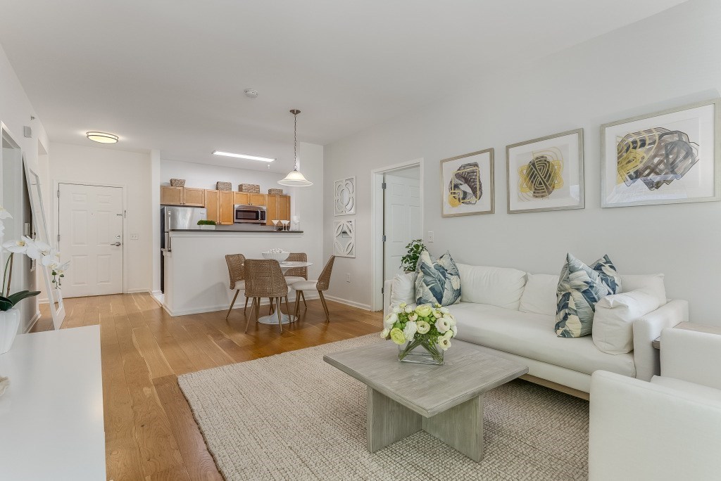 A living room with a white couch, a grey coffee table, and a dining table with chairs.