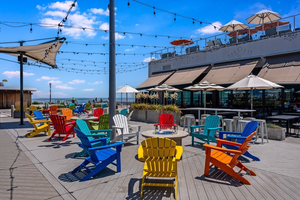 A row of colorful chairs are lined up on a wooden deck.